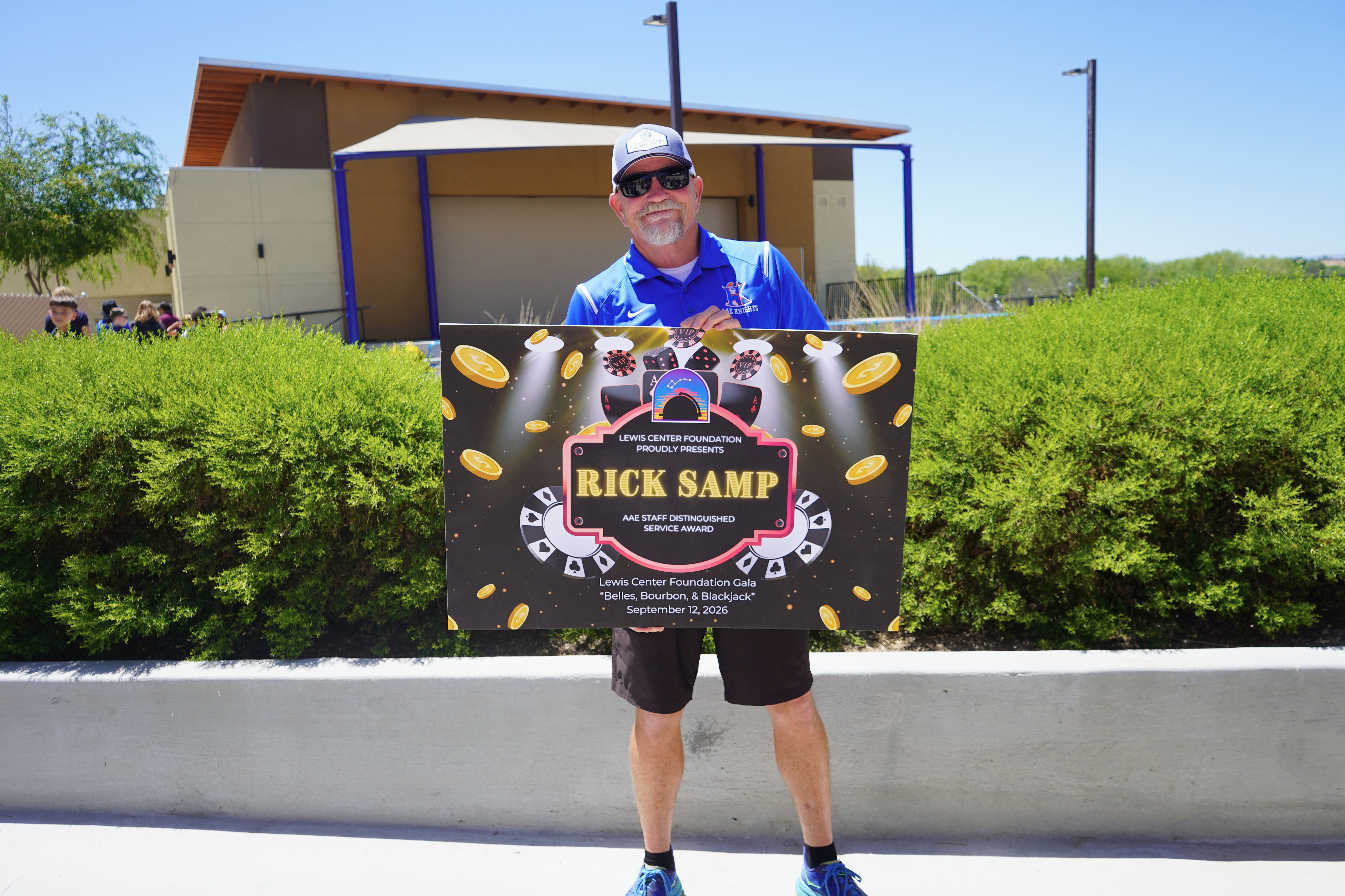photo of Coach Rick Samp holding 2026 Lewis Center Foundation Gala sign.