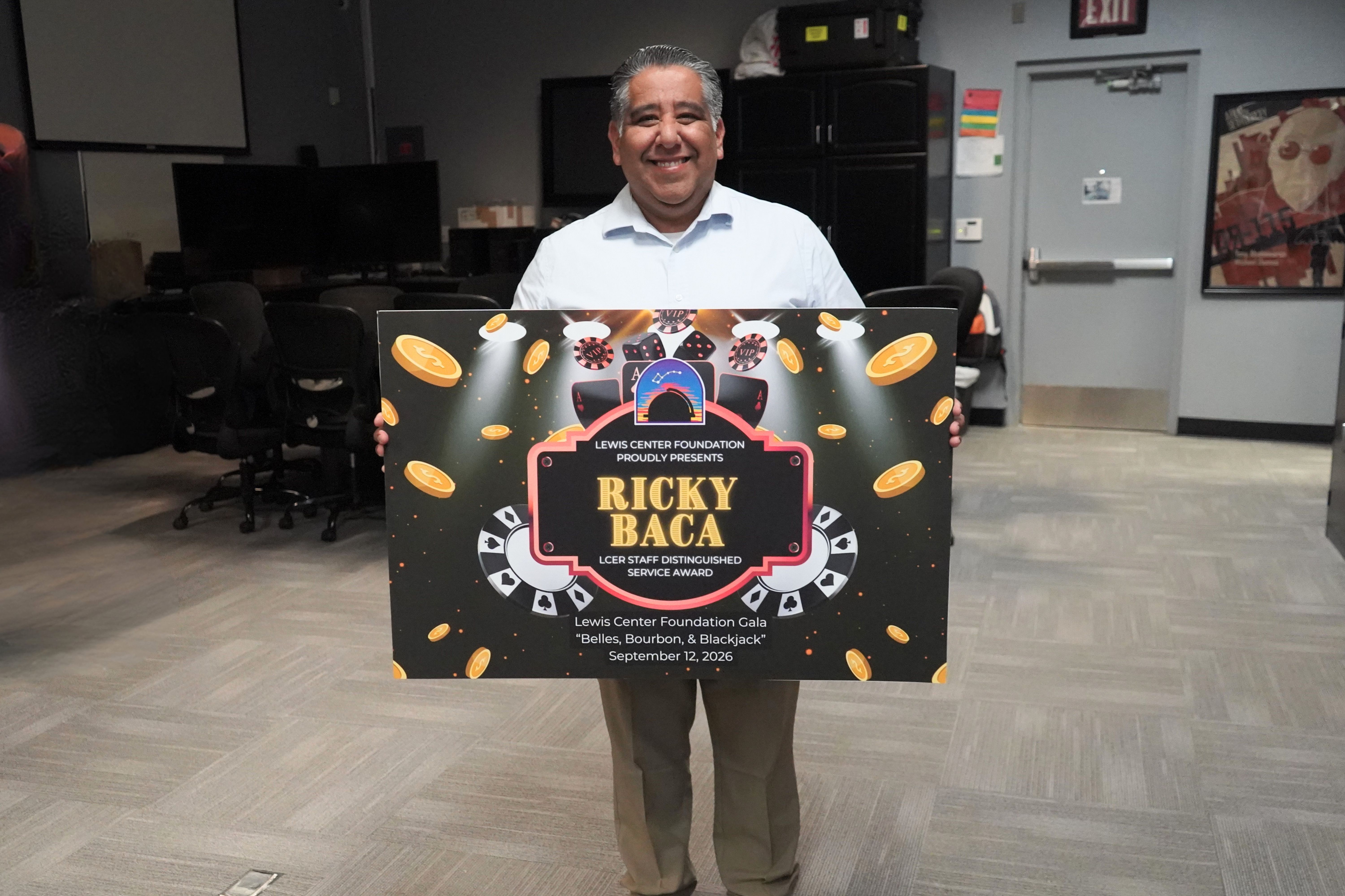 photo of Ricky Baca holding 2026 Lewis Center Foundation Gala sign.
